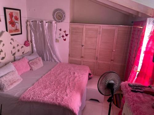Old Harbourapolts的卧室配有粉红色的床和风扇。