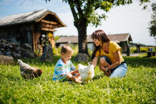 圣卡尼兹逊姆农庄体验酒店的一只小鸡坐在草地上的女人和小孩