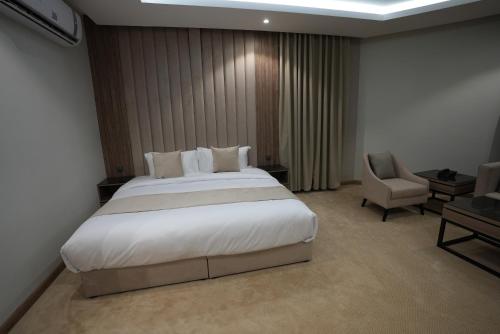利雅德Awrad Royal 2的卧室配有一张白色大床和一把椅子