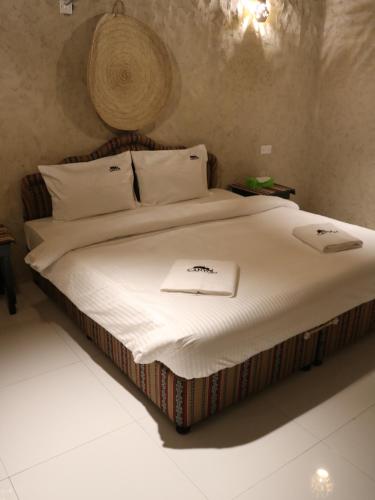 阿尔哈姆拉Canyon Rest House Jabal Shams的一张带白色床单和帽子的床