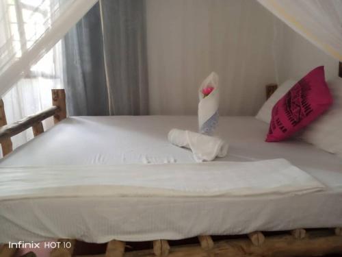 江比阿Jacob's Inn Jambiani的客房内的白色床和粉红色枕头