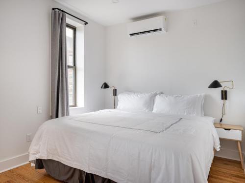 布鲁克林Modern Three Bedroom Brooklyn Condo-Hotel的白色卧室内的一张白色床,设有窗户