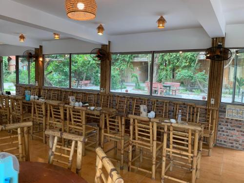 Xuân SơnHam Rong Bungalow的餐厅设有木桌和椅子以及大窗户。