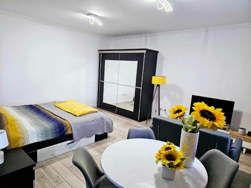 梅迪亚什Concept Urban的一间卧室配有一张床和一张桌子,上面摆放着向日葵
