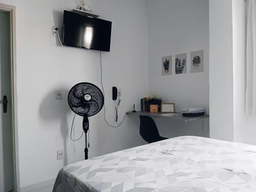 莫日-达斯克鲁济斯Apartamento Completo A25 Flat Centro的一间卧室配有一张床、一张桌子和风扇