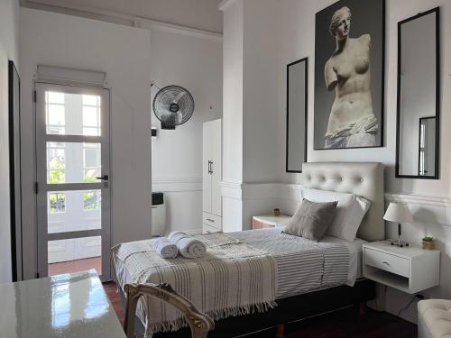 布宜诺斯艾利斯La Casa de Lola BA的卧室配有一张床铺,墙上挂着雕像