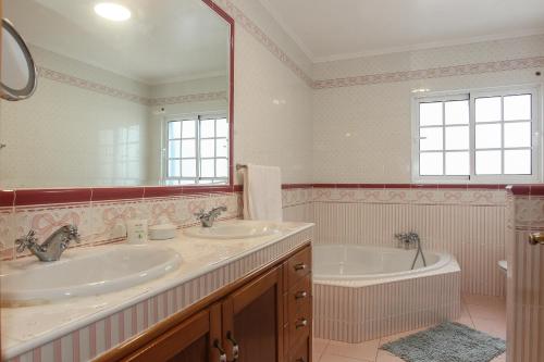 蓬塔德尔加达Capelas Blue , Relax & Fun - Up to 14 Guests!的浴室设有2个水槽、浴缸和镜子