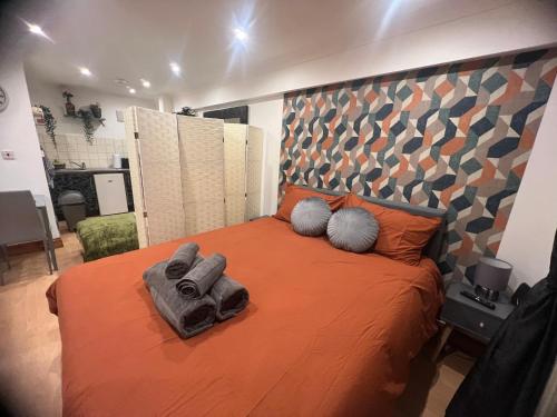 伦敦Nice StudioFLAT in London的一间卧室配有带橙色床单和枕头的床。