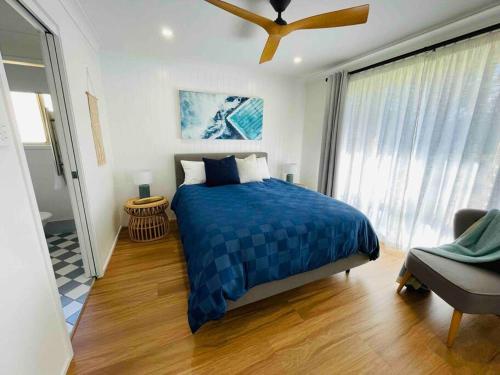文森提亚Tide 'n' Seek: Family Beach House with Games Room的一间卧室设有蓝色的床和窗户。