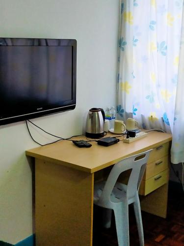 彭亨R2L5Y Room 3 with aircond + TV( share Toilet only)的一张桌子、一台电视和一张桌子及两把椅子