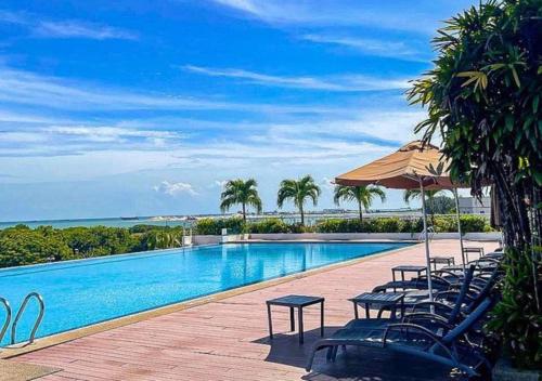 马六甲马六甲假日酒店的一个带椅子和遮阳伞的游泳池以及大海