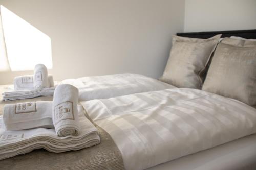 萨格勒布Hugo apartments的一张带毛巾和枕头的白色床