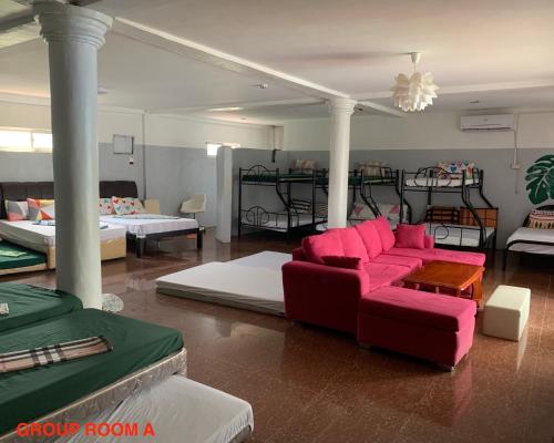莫龙Hana Natsu Resorts Beach & Hotel的一间带红色沙发的客厅和一间带床的房间