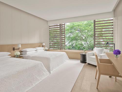 新加坡The Singapore EDITION的一间白色卧室,配有两张床和窗户