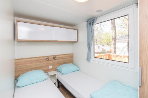 马内尔巴Albatross Mobile Homes on Camping Baia Verde的小型客房 - 带2张床和窗户
