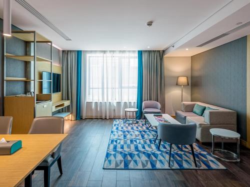 迪拜Flora Inn Hotel Dubai Airport的客厅配有沙发和桌椅