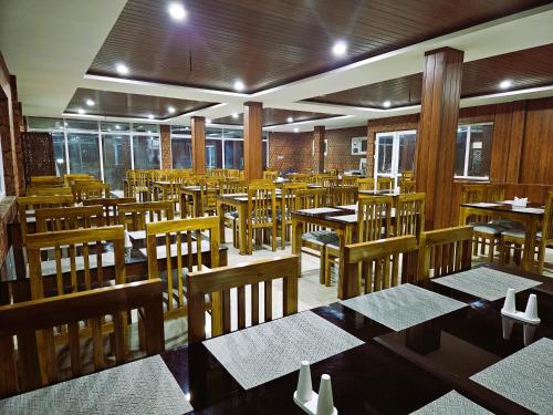 乌提Tulips Village Resorts的一间空餐厅,配有木桌和椅子