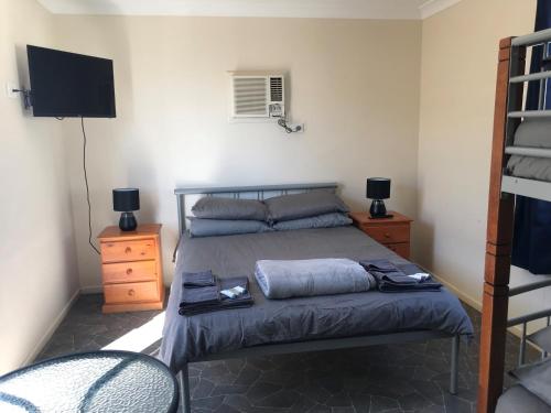 温顿Australian Hotel Winton Cabins的一间卧室配有一张带电视的床和一张位于郊区的床铺。