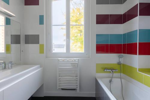 勒芒Villa Isaac - Luxueuse - Parking - 16p - Rêve au Mans的带浴缸、水槽和窗户的浴室