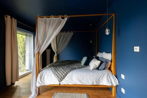 勒芒Villa Isaac - Luxueuse - Parking - 16p - Rêve au Mans的一间卧室配有一张天蓬床和蓝色的墙壁