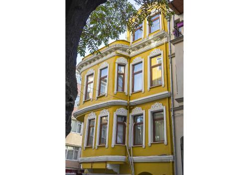 伊斯坦布尔Mar Suite的树旁的黄色建筑,有白色的窗户