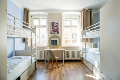 柏林EastSeven Berlin Hostel的客房设有两张双层床和一张书桌。