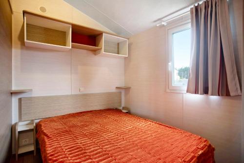 帕塔亚什Bungalow T2 i i i - 15 Min Nazaré的一间卧室配有一张带橙色棉被的床和窗户