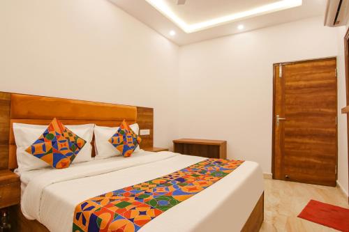 钱德加尔FabHotel Ambassador的一间卧室配有一张带色彩缤纷枕头的大床