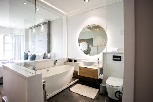 赫曼努斯Bayview 303的带浴缸、水槽和镜子的浴室