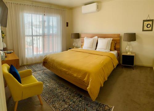 本迪戈Luxury Inner City Townhouse的一间卧室配有一张大床和一张黄色椅子