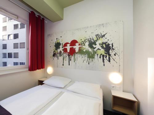 柏林B&B HOTEL Berlin-Potsdamer Platz的卧室配有一张床,墙上挂有绘画作品