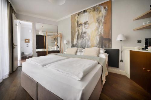 布拉格设计聂鲁达酒店的卧室配有一张大床,墙上挂有绘画作品