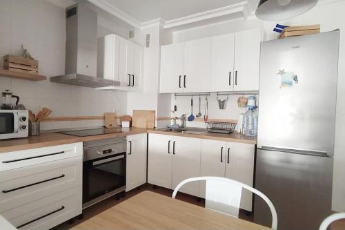 拉特吉塔Apartamento El Faro, Sotavento, playa la tejíta的厨房配有白色橱柜和不锈钢冰箱