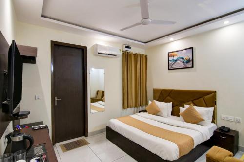 新德里Hotel De Hocks Deluxe - New Delhi的一间卧室配有一张床和一台电视