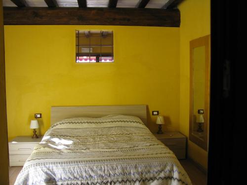 马罗内Chalet della Rota的黄色卧室设有床和2扇窗户