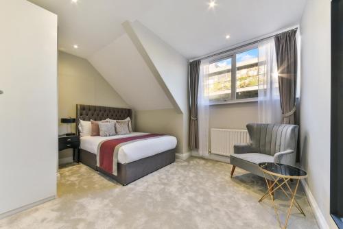 伦敦Avari Apartments - Hatton Collection的卧室配有床、椅子和窗户。