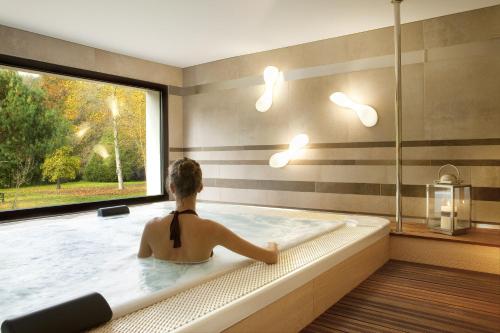 Saint-Ouen-les-Vignes罗比尼尔餐厅及水疗酒店 的坐在浴缸里的女人,有窗子