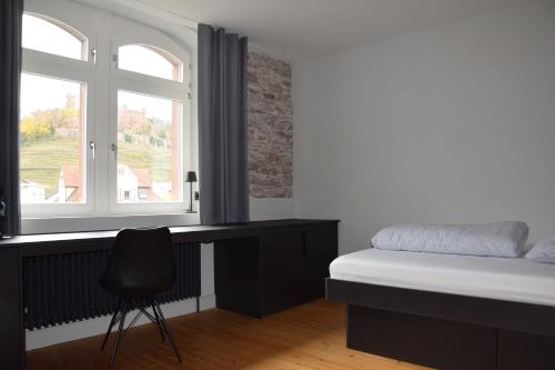 奥滕贝格Alter Bahnhof Ortenberg的一间卧室配有一张床、一张书桌和一个窗户。