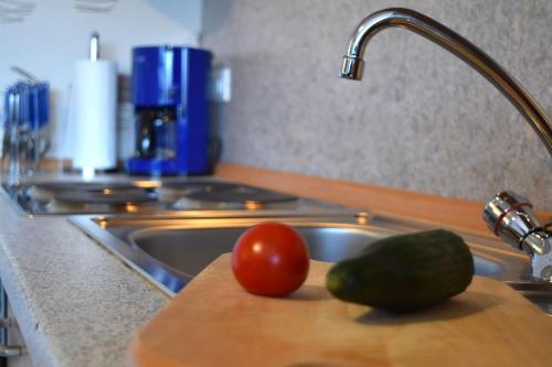 梅德巴赫Ferienwohnung Martina的厨房水槽,在切板上放有西红柿和黄瓜