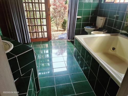 MtubatubaGREEN TREE的带浴缸的浴室和绿色瓷砖地板。