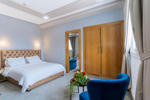 盖尼特拉Hotel Mamora Kénitra的一间卧室配有一张床和一张蓝色椅子