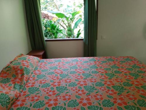 VaïareFare Mihimana的一间卧室配有一张带花卉床罩的床和窗户。