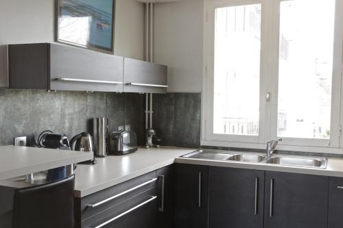 波尔多Grand Lebrun - Appartement 3 chambres avec ascenseur - Caudéran的厨房配有黑色橱柜、水槽和窗户。