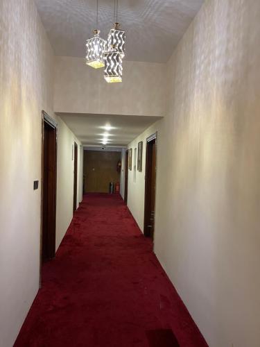 巴格达Al-Rabie Hotel & Apartments的走廊上一条铺有红地毯的长走廊