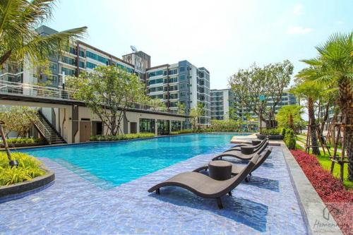 Ban Khlong Samrong素坤逸展會雅居樂酒店式公寓的一座大楼前的游泳池,配有躺椅