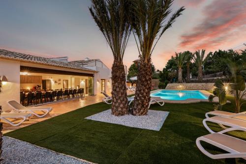 卡尔佩Villa Joan - PlusHolidays的后院拥有两棵棕榈树和游泳池