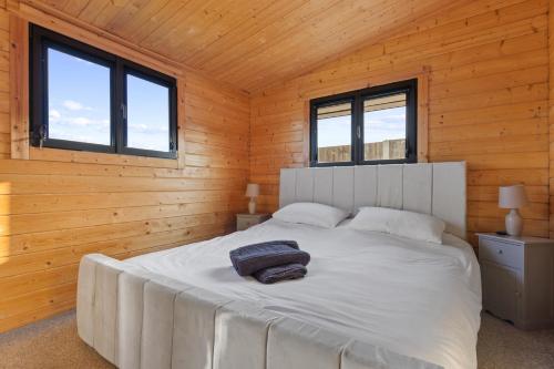 SlindonCholler Farm Lodge - Private Hot Tub的木制客房内的一间白色床卧室