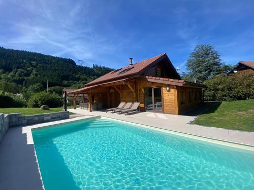 普兰凡Gîte Chalet avec bain nordique et piscine 11 pers Hautes Vosges的大楼前带游泳池的房子