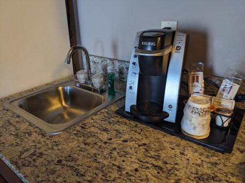 圣克劳德格兰德斯戴住宿套房酒店的厨房柜台配有咖啡壶,旁边是水槽