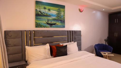 拉各斯BOL LODGE AND APARTMENT的卧室配有一张床,墙上挂有绘画作品